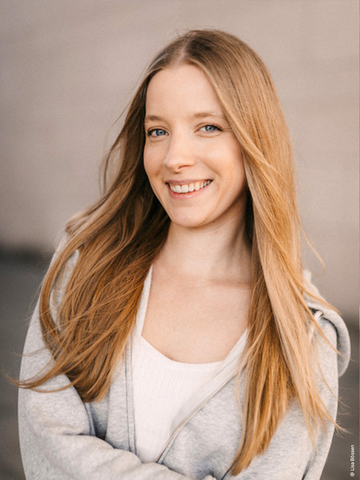 Cindy Klink in einem weißen Hoodie vor einer unscharfen, beigen Wand.